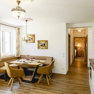 Der Essbereich in der Ferienwohnung mit Eckbank, gedecktem Tisch und Zugang zum Schlafzimmer.