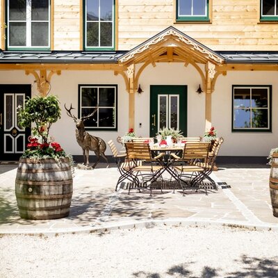 Die Terrasse der Appartements mit Außensitzgelegenheiten und dekorativen Pflanzen in Weinfässern.