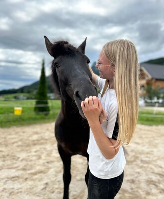 Ein Mädchen streichelt ein Pferd auf dem Gelände der Ap­par­te­ments.