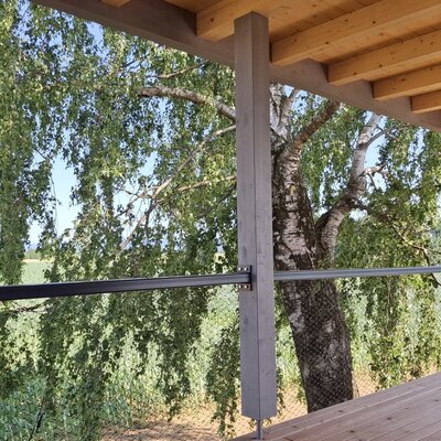 Balkon des Ferienhauses mit Holzboden und Blick auf eine Birke und Felder.