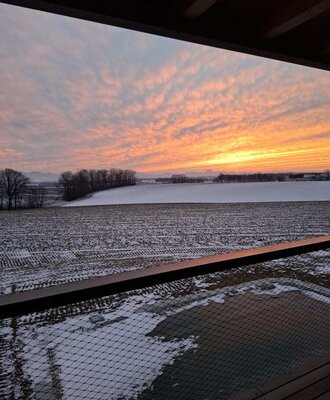 Sonnenuntergang über der verschneiten Landschaft, gesehen vom Balkon des Ferienhauses mit Sicherheitsnetz.