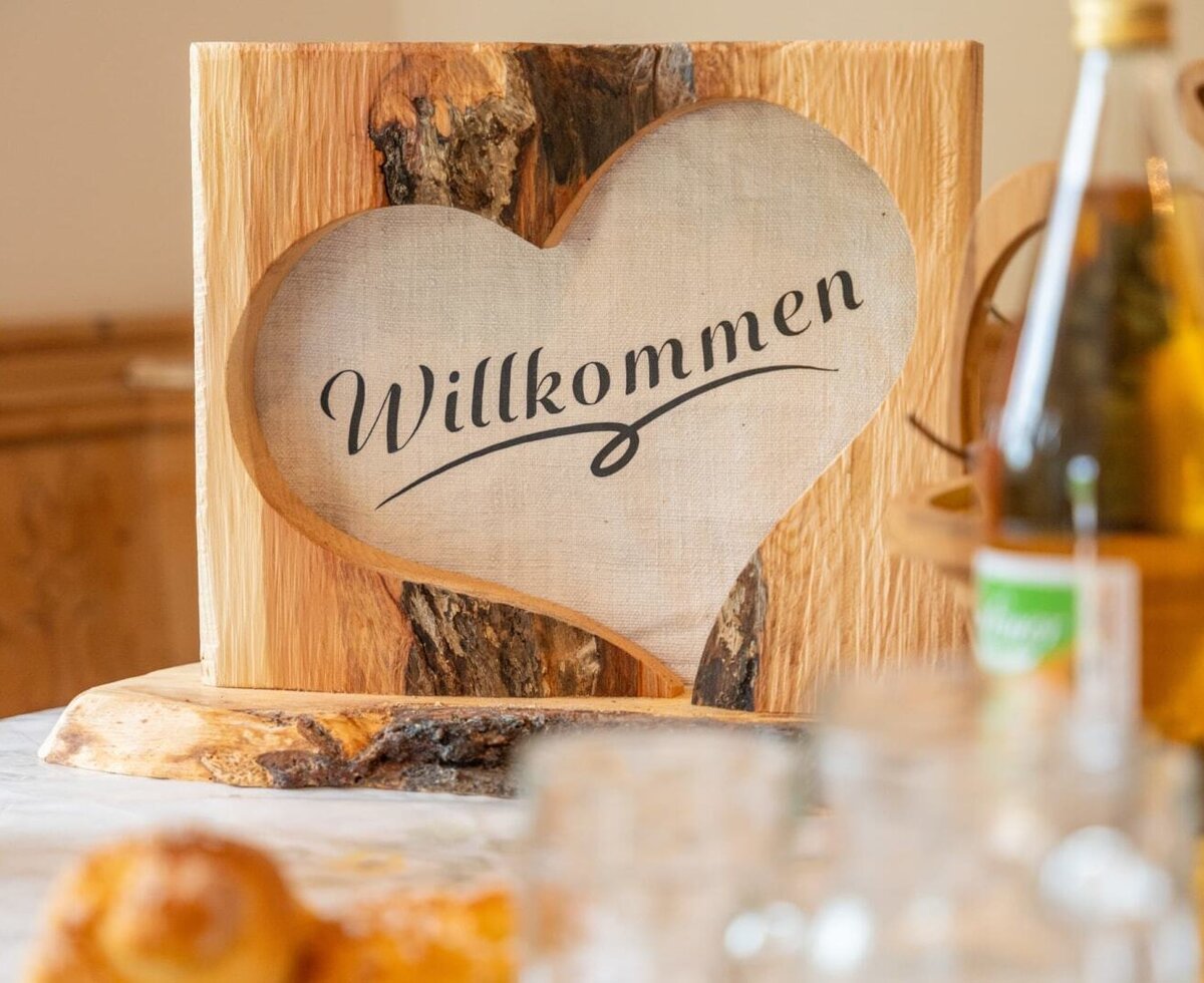 Ein herzliches, aus Holz gestaltetes Willkommensschild empfängt die Gäste im Bauernhof.