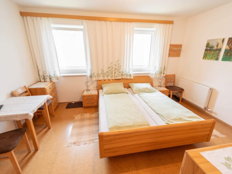Helles Doppelzimmer Herbst mit Holzmöbeln, gemütlicher Sitzecke und freundlichem Tageslicht.