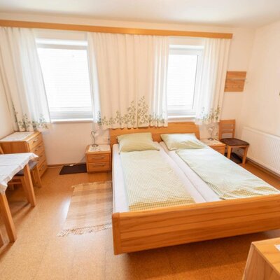 Helles Doppelzimmer Herbst mit Holzmöbeln, gemütlicher Sitzecke und freundlichem Tageslicht.