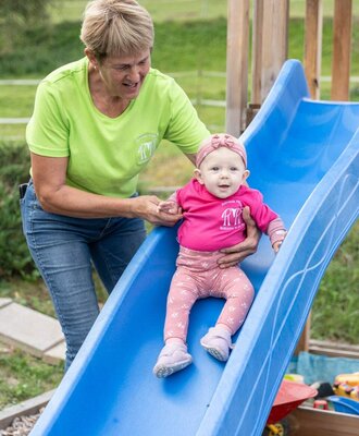 Der einladende Spielplatz des Bauernhofs mit einer blauen Kinderrutsche für die kleinen Gäste.