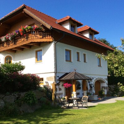 Der Bauernhof mit blumengeschmücktem Balkon, Garten und einem möblierten Sitzbereich im Freien.