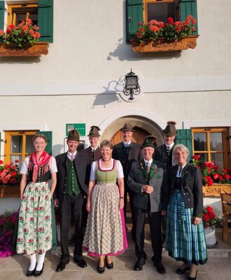 Die Gastgeberfamilie des 4-Sterne-Bauernhofs in traditioneller Tracht vor dem Gebäude.