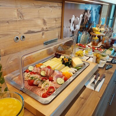 Das Frühstücksbuffet im Bauernhof bietet eine Auswahl an Käse, Aufschnitt, Marmeladen und frischen Getränken.