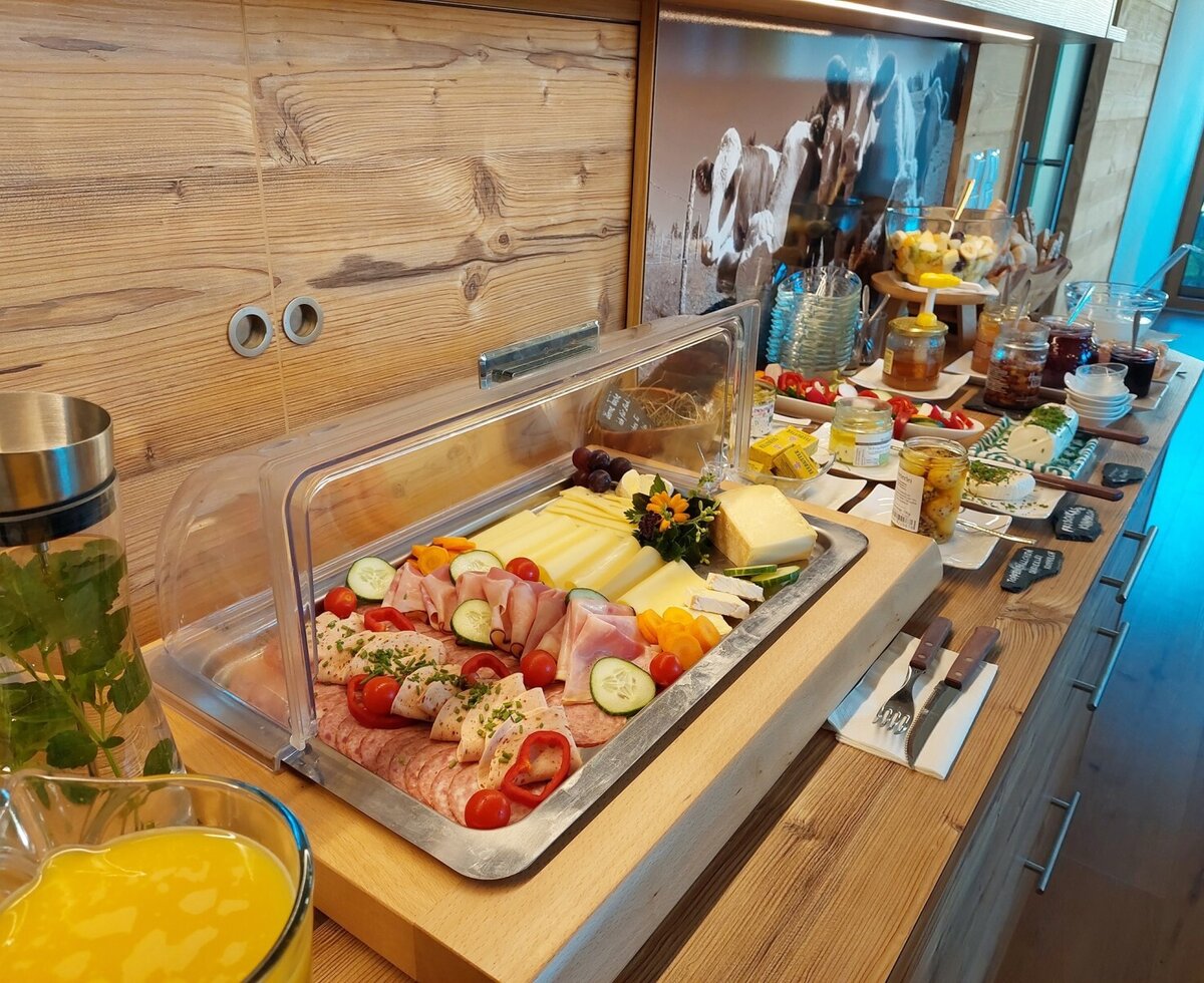 Das Frühstücksbuffet im Bauernhof bietet eine Auswahl an Käse, Aufschnitt, Marmeladen und frischen Getränken.