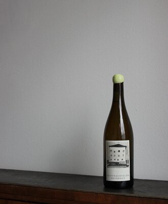 Eine edle Flasche des hauseigenen Weins auf einem rustikalen Holzschrank im Weinhaus.