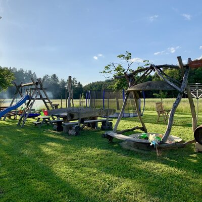 Der großzügige Garten des Bauernhofs mit einem einladenden Kinderspielplatz samt Rutsche, Trampolin und gemütlicher Holzsitzgruppe.
