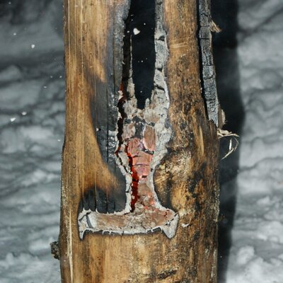 Ein brennender Holzstamm mit glühenden Kohlen im Schnee auf dem Bauernhof.