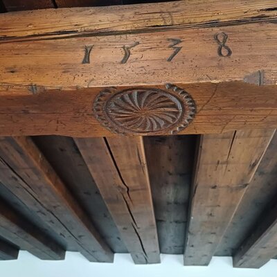 Die Holzbalkendecke in der Almhütte mit der eingeschnitzten Jahreszahl 1738 und einer dekorativen Rosette.