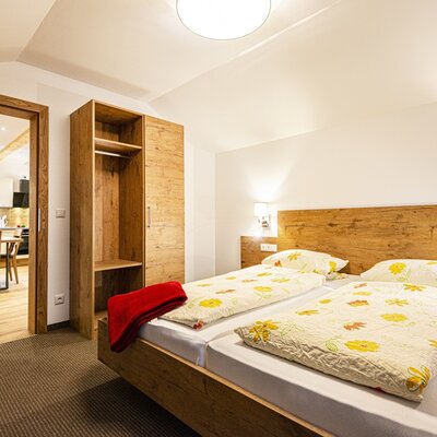Schlafzimmer im Bauernhof mit Doppelbett, Holzmöbeln und direktem Zugang zur Küche mit Essbereich.