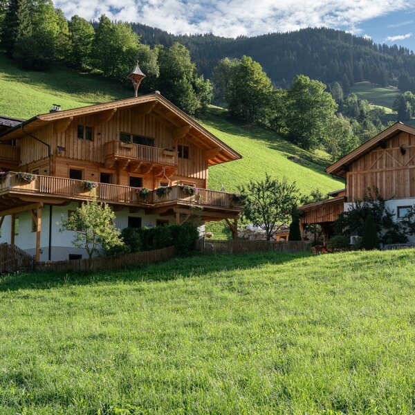Der charmante Bauernhof eingebettet in eine saftig grüne Wiese vor einer malerischen Bergkulisse.