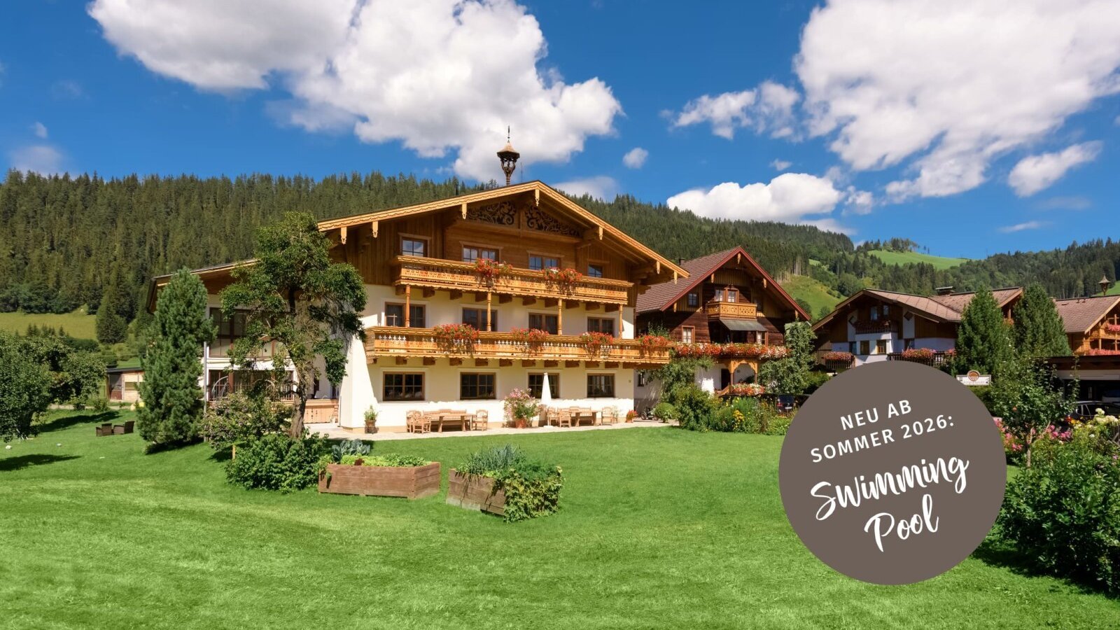 Die beiden traditionellen Bauernhäuser mit Balkonen, umgeben von einer grünen Wiese und Berglandschaft.