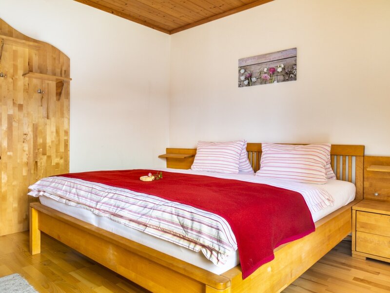 Das Schlafzimmer im Bauernhof verfügt über ein Doppelbett mit Holzrahmen, Nachttische und eine hölzerne Wandgarderobe.