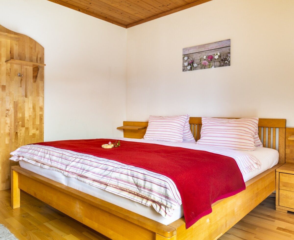 Das Schlafzimmer im Bauernhof verfügt über ein Doppelbett mit Holzrahmen, Nachttische und eine hölzerne Wandgarderobe.