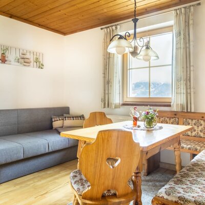 Essbereich im Appartement des Bauernhofs mit Holz-Eckbank, Tisch und Schlafsofa.