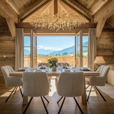 Essbereich im Bauernhof mit Holzbalken, einem Tisch für acht Personen und direktem Zugang zum Balkon mit Bergblick.