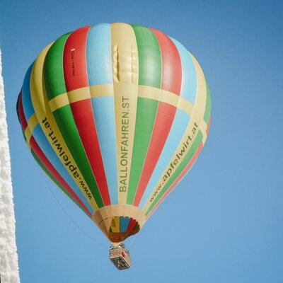 Ein farbenfroher Heißluftballon am klaren Himmel, der eine mögliche Freizeitaktivität in der Region des Bauernhofs darstellt.