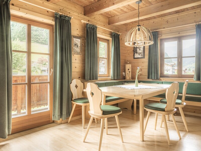 Ein gemütlicher Essbereich im Bauernhof mit einer rustikalen Eckbank aus Holz, passenden Stühlen und viel natürlichem Tageslicht.
