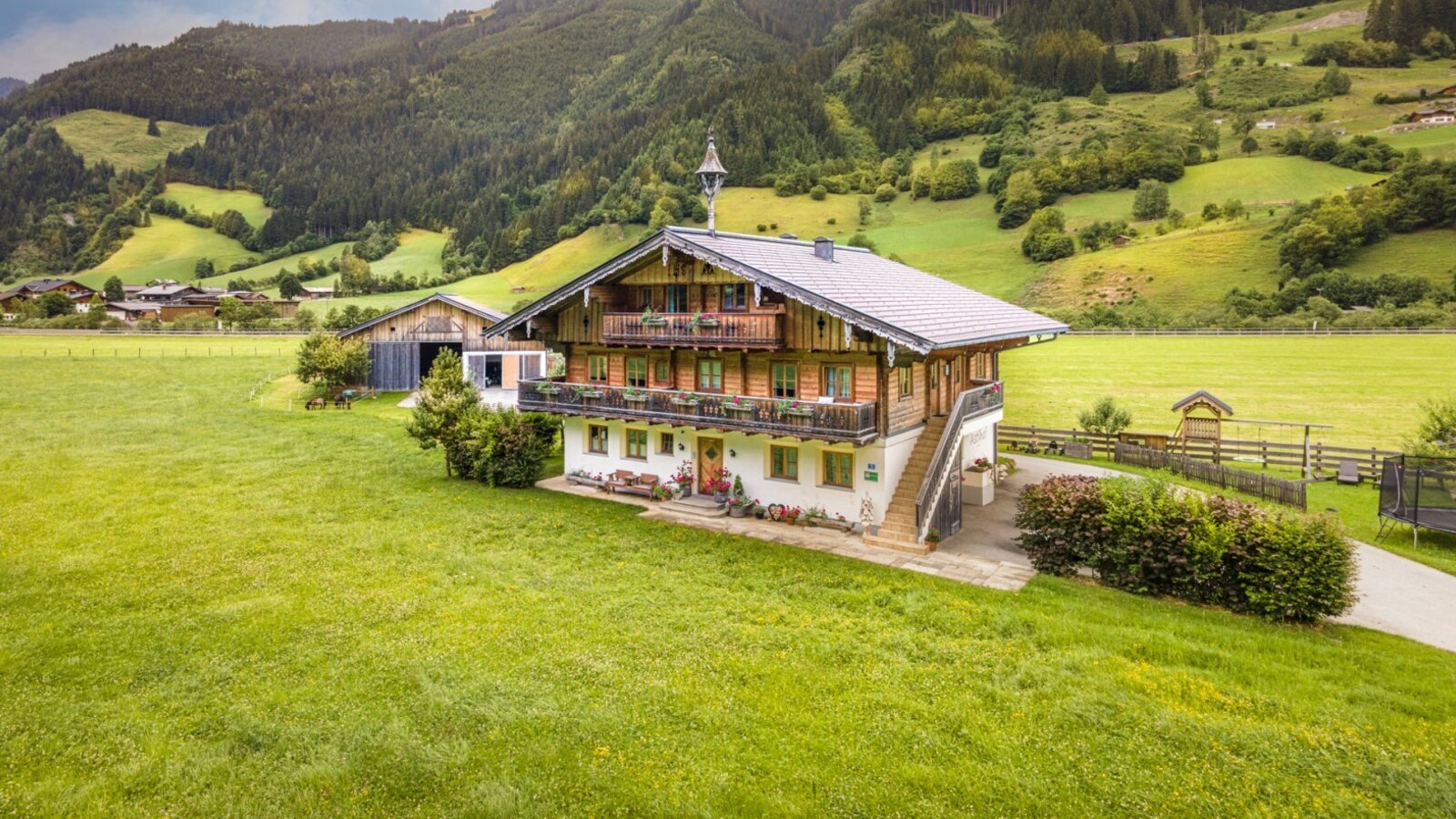 Der einladende Bauernhof inmitten von saftig grünen Wiesen und einer malerischen Bergkulisse.
