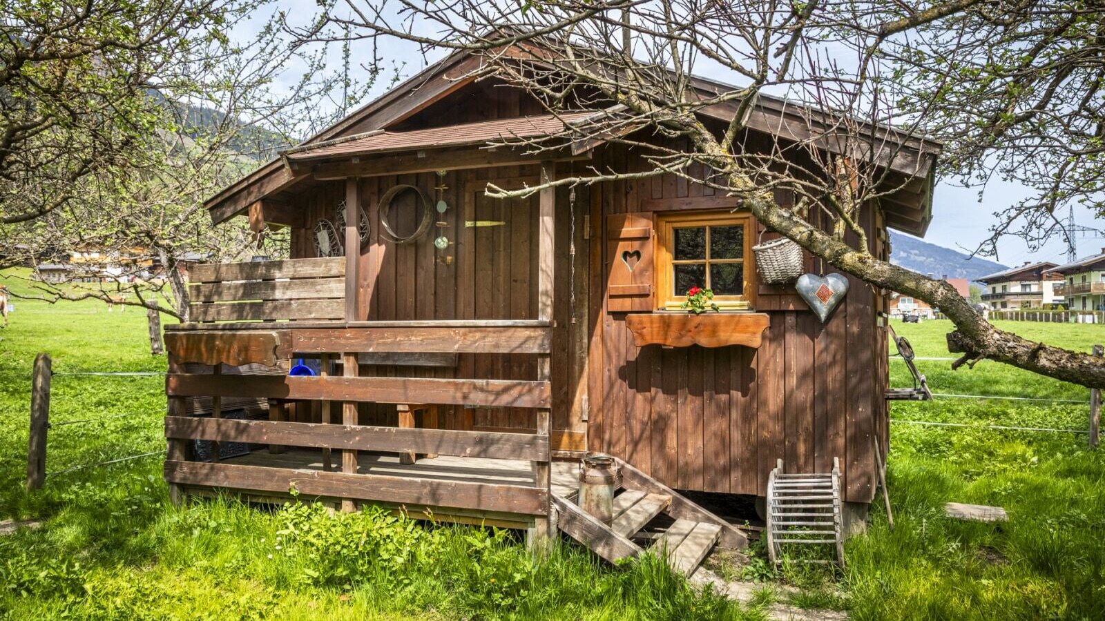 Kleines Holzhaus mit Veranda und Blumenkasten im Gartenbereich der Ap­par­te­ments.