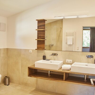 Das Badezimmer des Bauernhofs verfügt über zwei Waschbecken, einen großen Spiegel, eine Dusche mit Glastrennwand und ein WC.