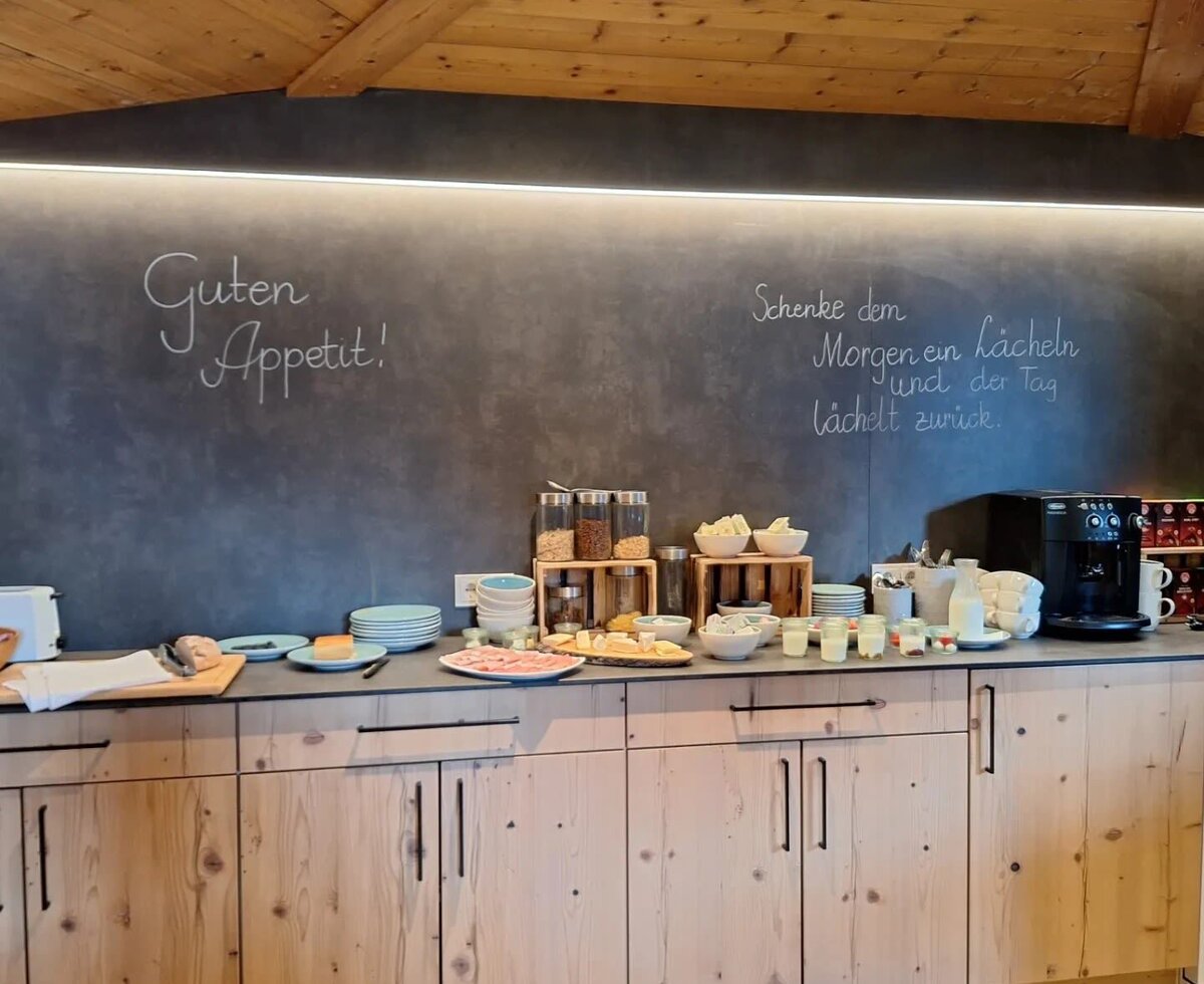 Das Frühstücksbuffet im Aufenthaltsraum des Bauernhofs mit einer Auswahl an Wurst, Käse, Müsli und frischem Brot.