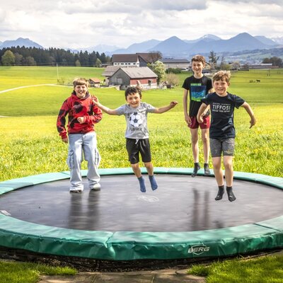 Ein Trampolin für Kinder auf dem Bauernhof mit Blick auf die Berge.