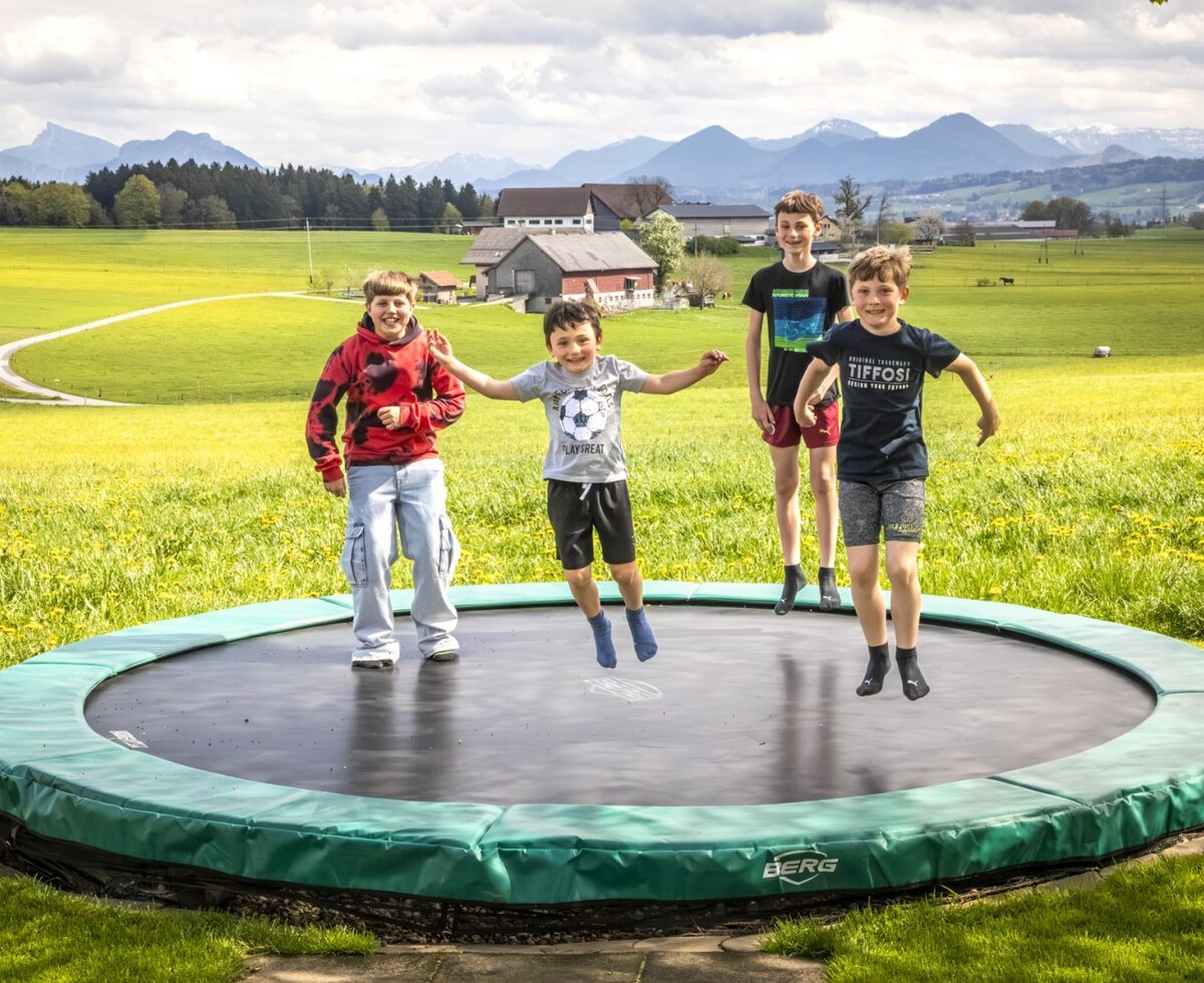 Ein Trampolin für Kinder auf dem Bauernhof mit Blick auf die Berge.