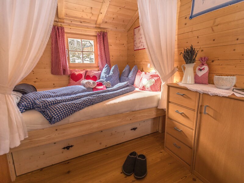 Schlafzimmer im Bauernhof mit einem Einzelbett, Holzverkleidung, integrierten Bett-Schubladen und einem Holzschrank.