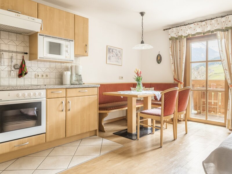 Voll ausgestattete Küche und Essbereich im Bauernhof mit Zugang zum Balkon und Bergblick.