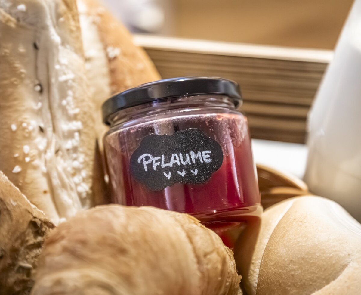 Bauernhof-Frühstück mit frischem Brot, Brötchen, Croissant, Pflaumenmarmelade und Milch.