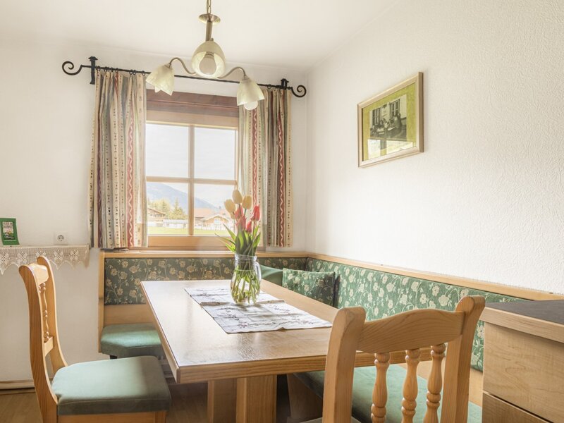 Essbereich in der Ferienwohnung des Bauernhofs mit Holztisch, Eckbank und Fensterblick ins Grüne.
