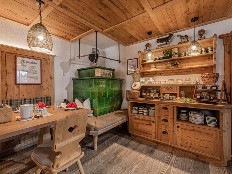 Die Bauernstube mit Holztisch, Sitzbänken, grünem Kachelofen