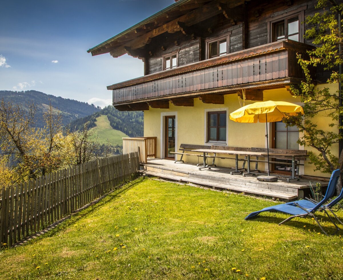 Der eigene Gartenbereich der Ferienwohnung im Bauernhaus mit Terrasse, Sitzgelegenheiten und Sonnenliegen bietet einen Blick auf Wald und Wiesen.