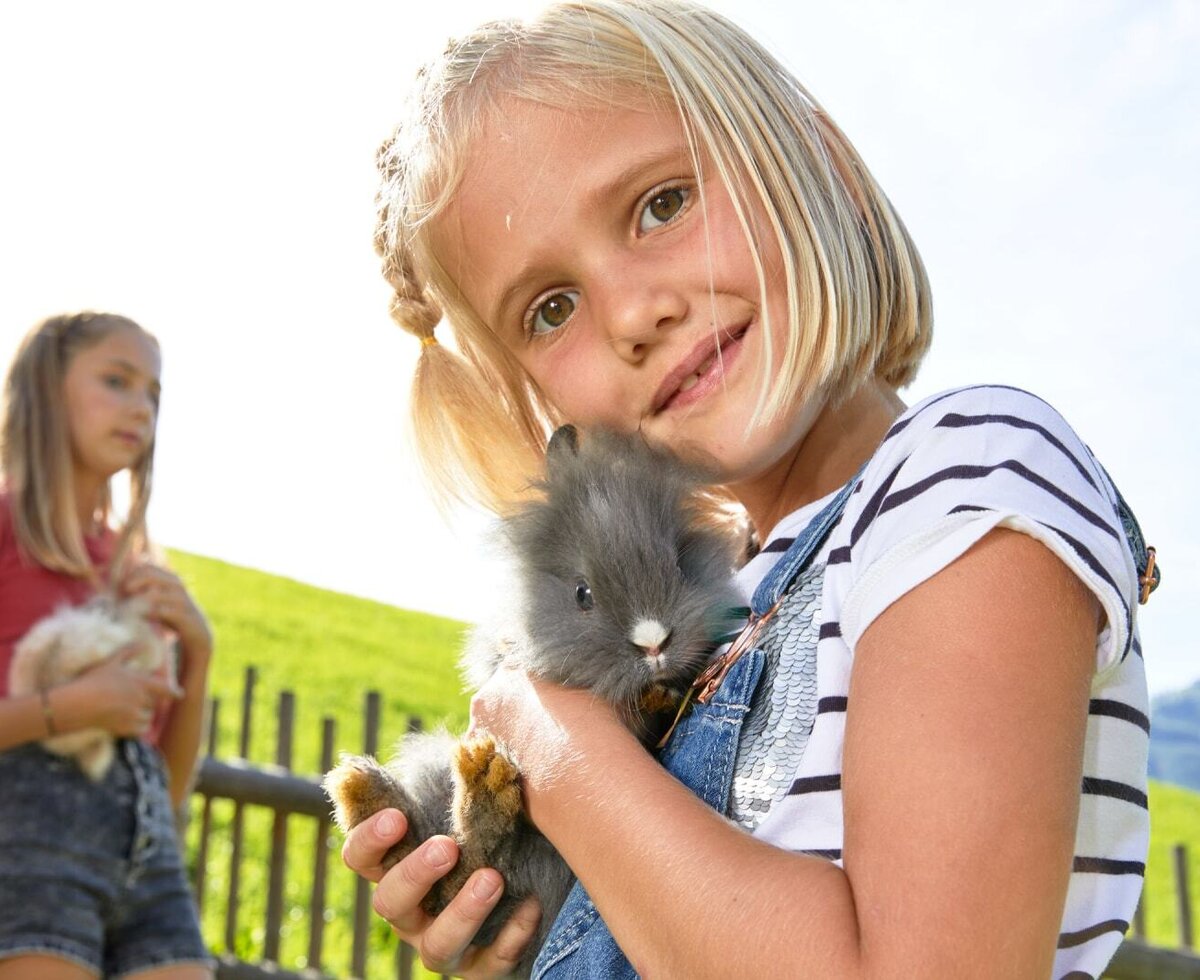Kinder halten Kaninchen auf dem Bauernhof.