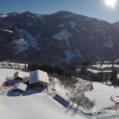 Der Hof in einer verschneiten Berglandschaft mit Blick auf die umliegenden Berge.