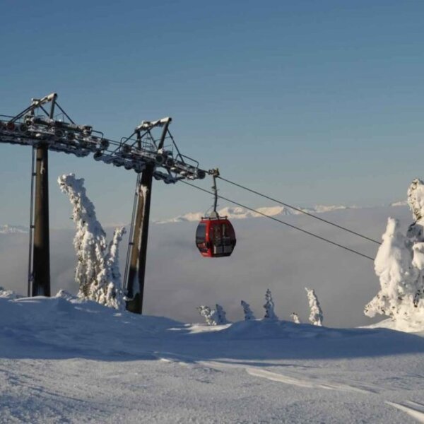 Gondelbahn in einer verschneiten Berglandschaft mit Blick auf die Wolkendecke.