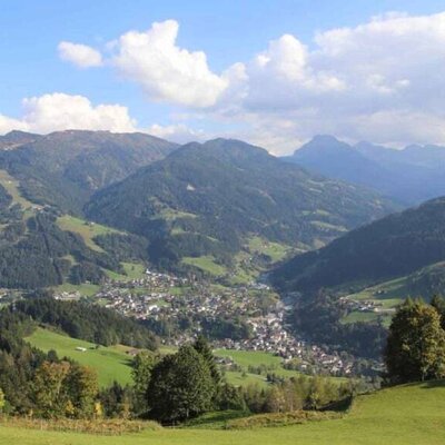 Blick von der Ferienwohnung auf das Bergpanorama mit einem Dorf im Tal und grünen Hängen.