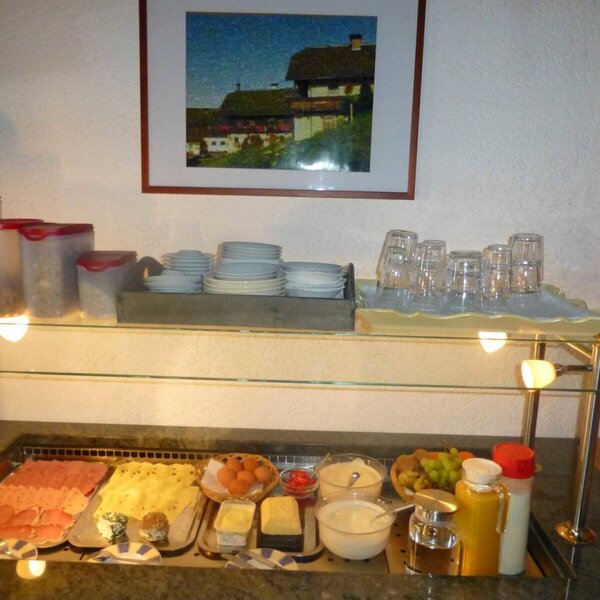 Frühstücksbuffet der Ferienwohnung mit Aufschnitt, Käse, Eiern, Müsli, Joghurt, Obst und Getränken.