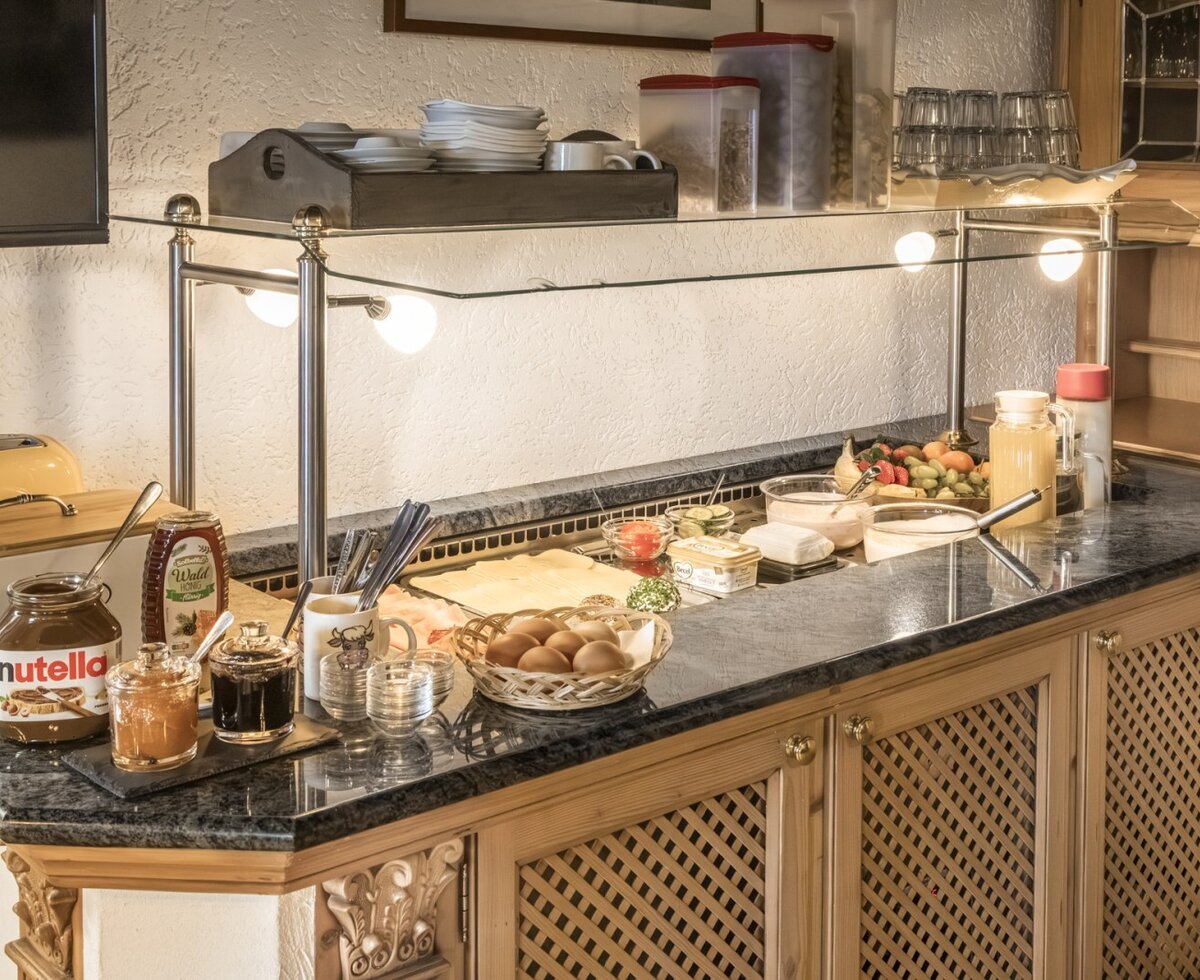 Frühstücksbuffet der Ferienwohnung mit Auswahl an Aufschnitt, Käse, Marmeladen, Nutella, Honig, Eiern, Obst, Joghurt und Säften.