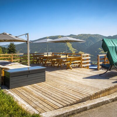 Die sonnige Holzterrasse der Ferienwohnung lädt mit gemütlichen Sitzgruppen, einer Liegewiese und einem herrlichen Bergblick zum Entspannen ein.