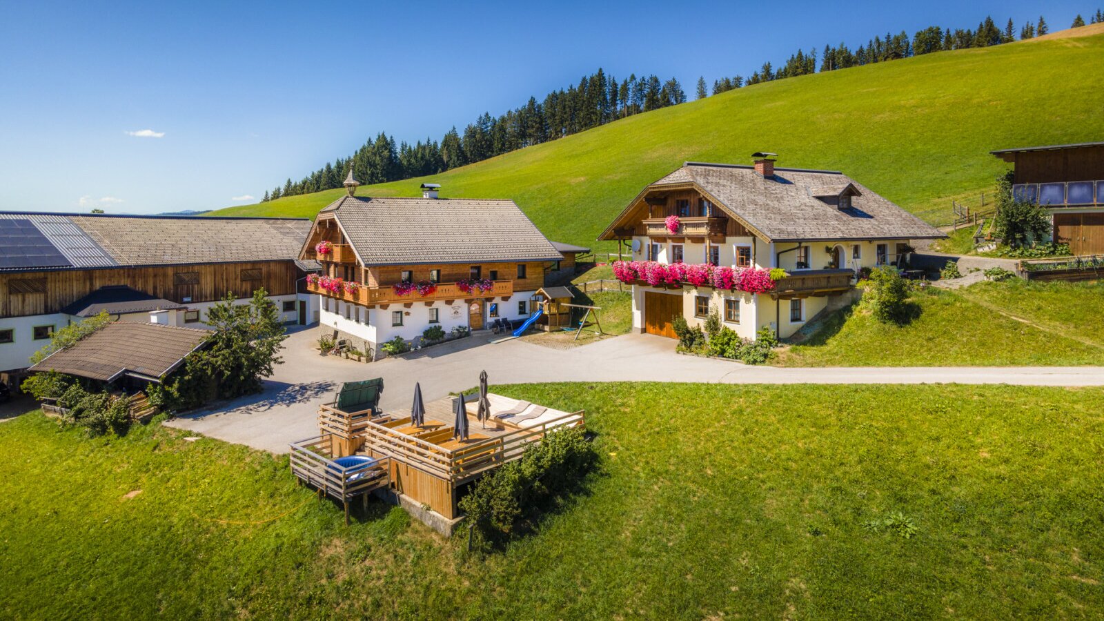 Die einladende Ferienwohnung inmitten einer idyllischen Berglandschaft mit großzügigen Wiesen und einer sonnigen Holzterrasse.