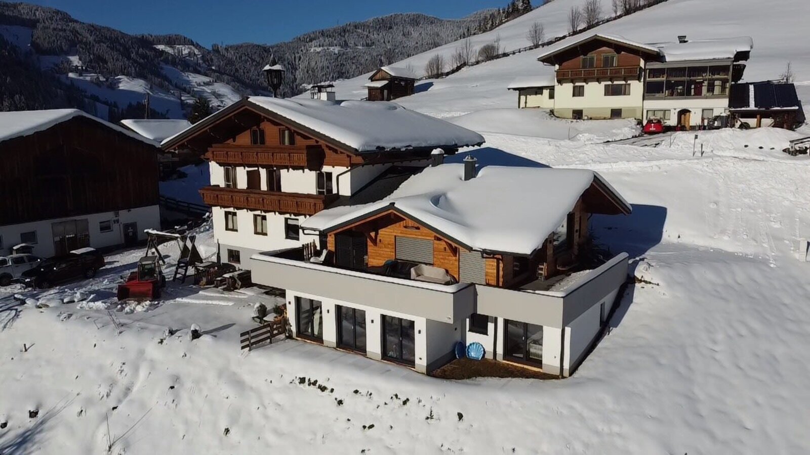 Der Bio Bauernhof Oberbenk im Winter, mit schneebedeckten Gebäuden und umliegender Berglandschaft.