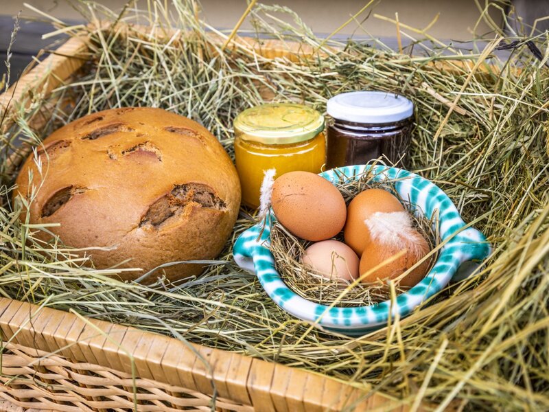Frisches Bauernbrot, Eier und hausgemachte Marmelade im Heukorb als Teil des Angebots auf dem Bauernhof.