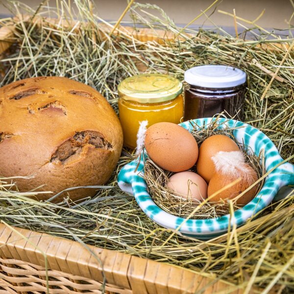Frisches Bauernbrot, Eier und hausgemachte Marmelade im Heukorb als Teil des Angebots auf dem Bauernhof.