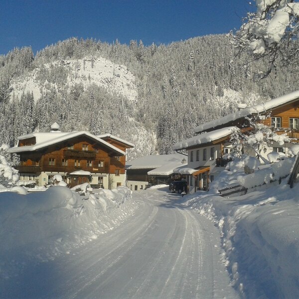 Der schneebedeckte Bauernhof in einer winterlichen Berglandschaft.
